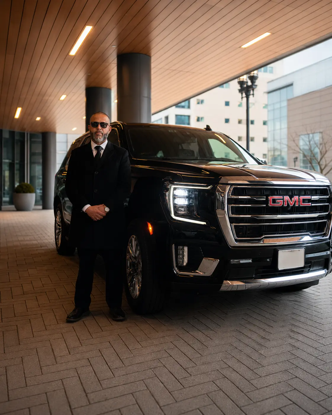 Professional chauffeur beside a private airport transportation vehicle.